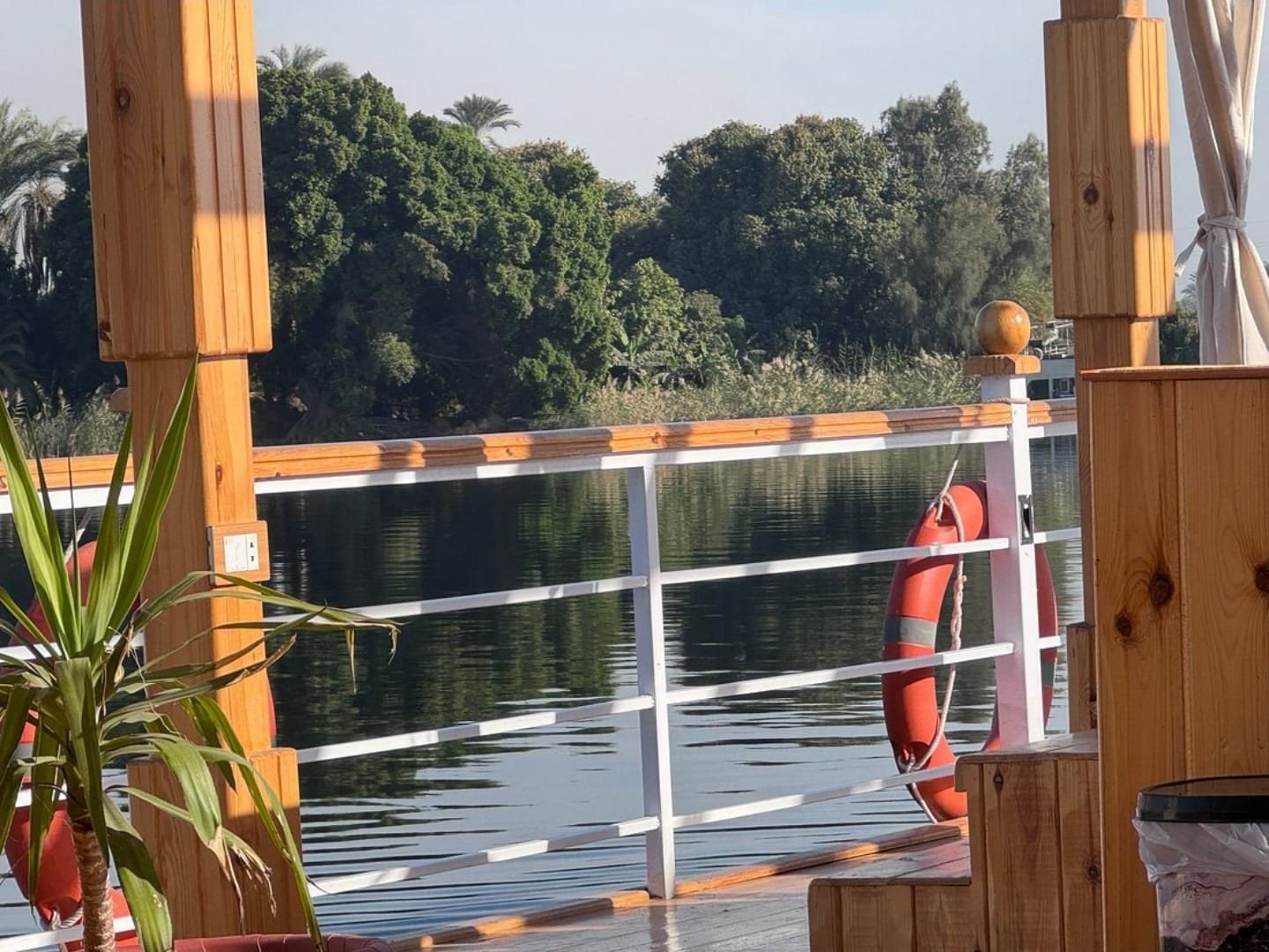 Cubierta de la dahabiya Akhenaton frente a una orilla verde
